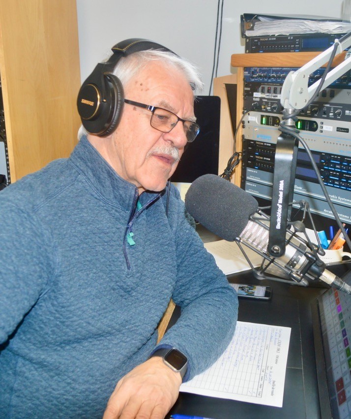 Photo of Bruno at his radio host desk with large microphone.