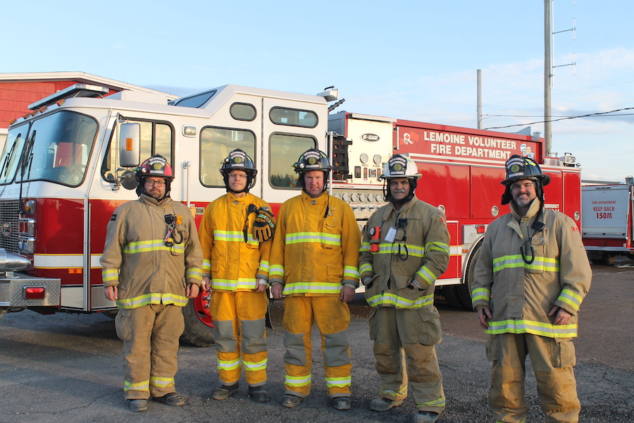 Jason Aucoin, Brad Purdon, Keith Aucoin, Alfred Aucoin, and Jeremy Smith posing for a photo in their firefighter gear in front of a fire truck.