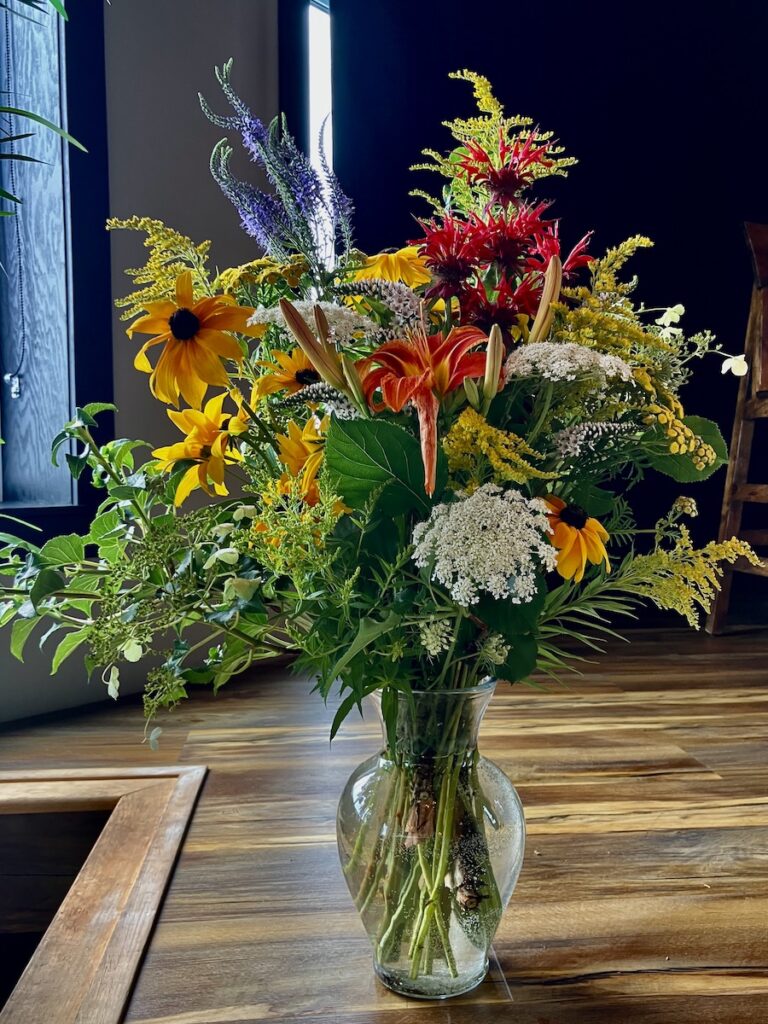 Photo of a vase full of flowers sitting on a counter.